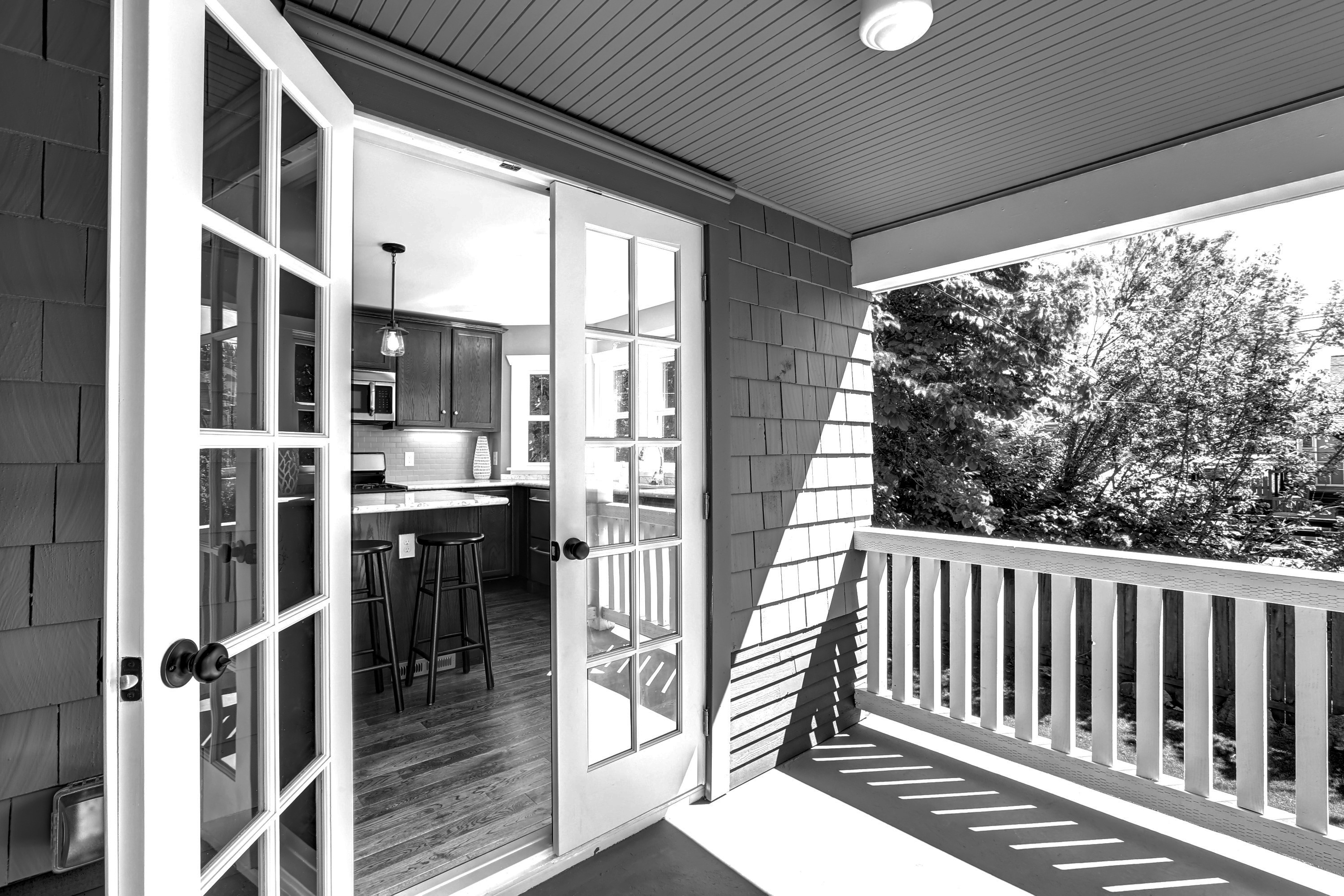Black-and-white detail of a porch with french doors on a single-family home